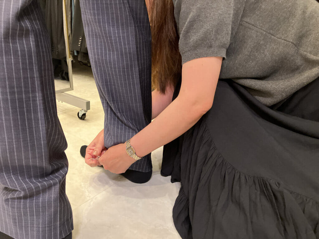 お客様のパンツの裾上げをするスタッフ